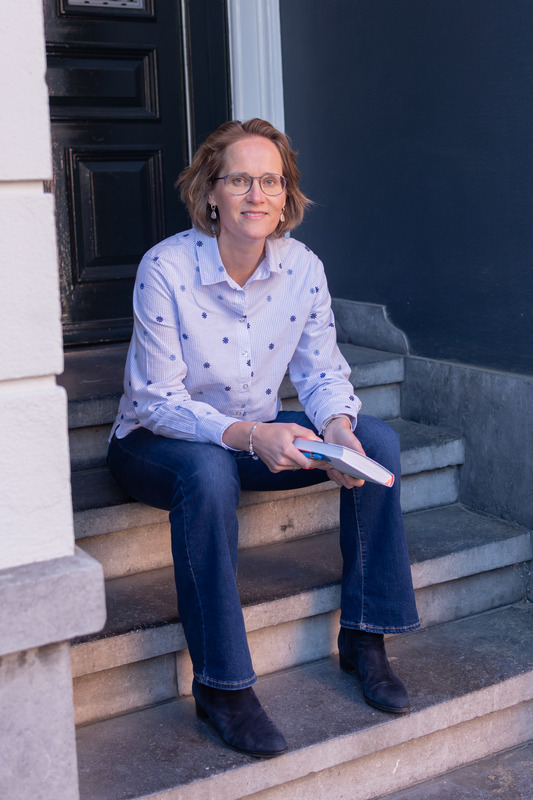 Tekstschrijver zit op trap voor huis met schrijfblok in de hand